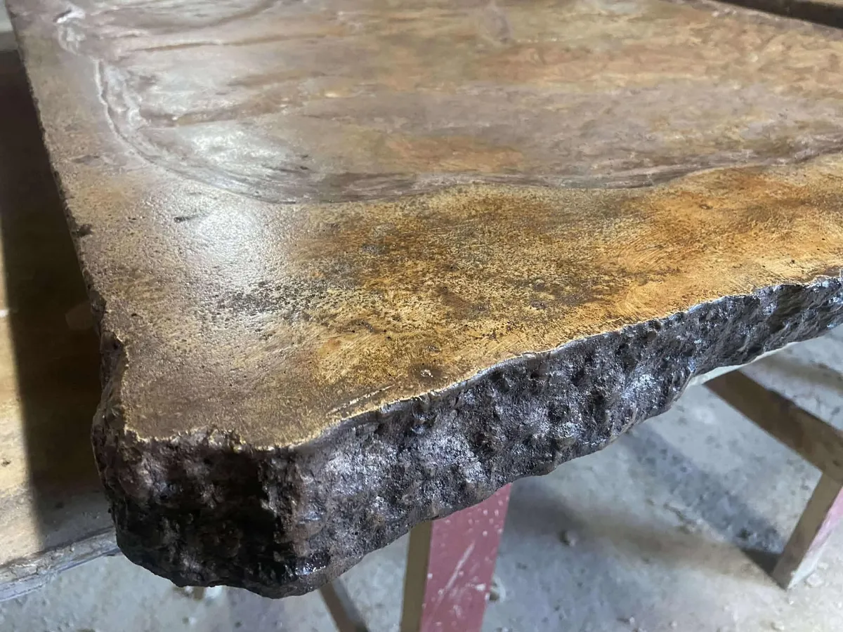 Close detail of a textured custom concrete countertop with a live edge.