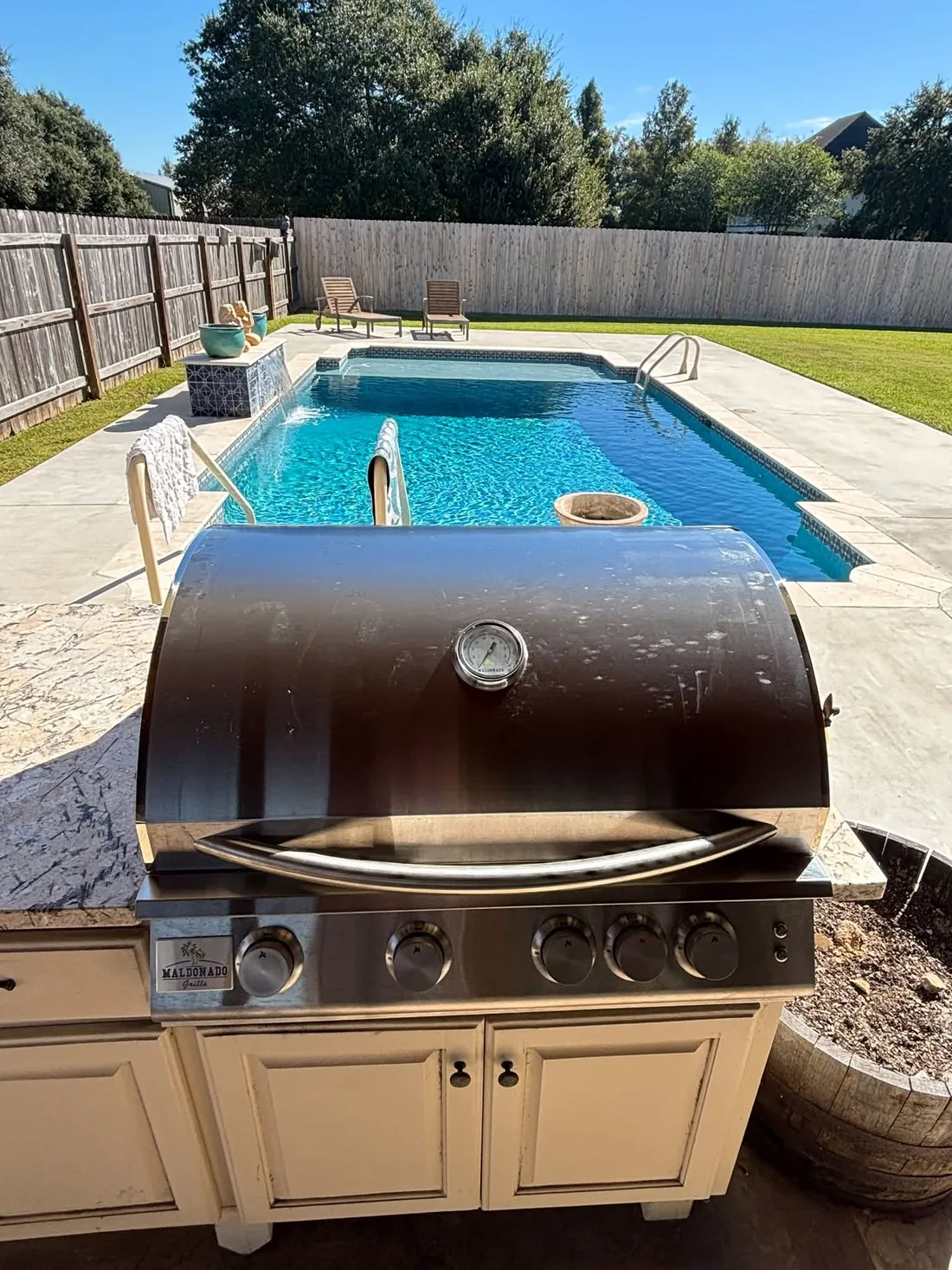 32-inch Maldonado Grill fitted into beige outdoor kitchen cabinetry beside a swimming pool.